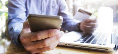 a man holding a credit card while using a laptop.
